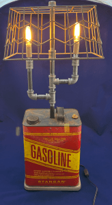 Gasoline can lamp with two bulbs (lit) and wire basket shade.